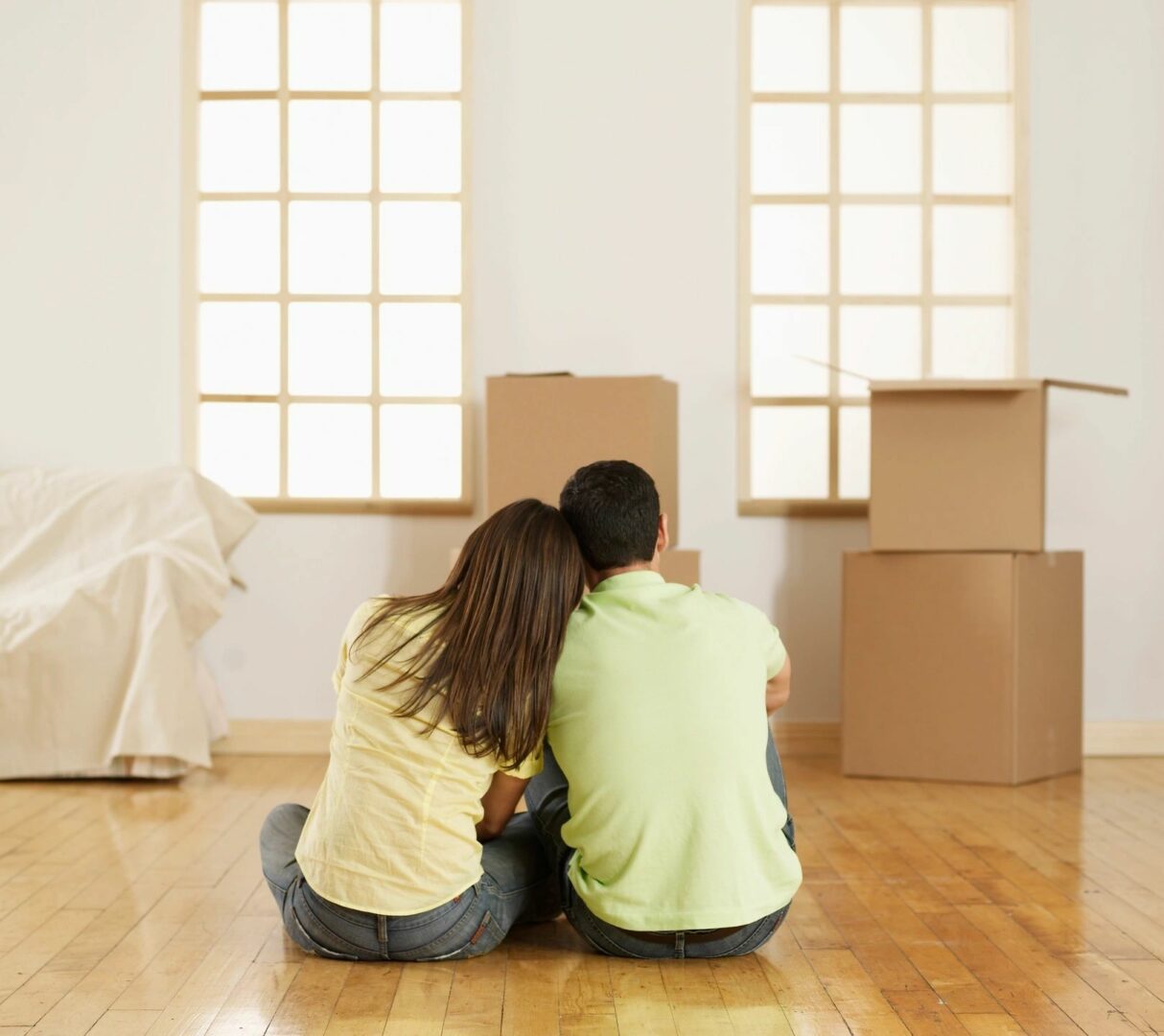 A couple sitting on the floor in front of boxes.